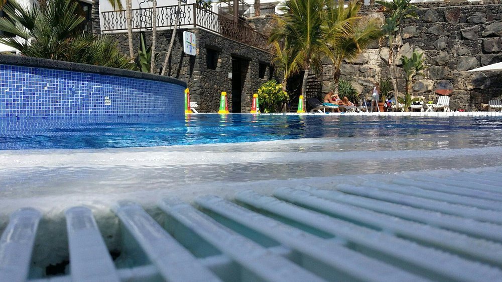 Outdoor swimming pool at luxury Hotel Fariones Lanzarote with volcanic stone architecture and palm t